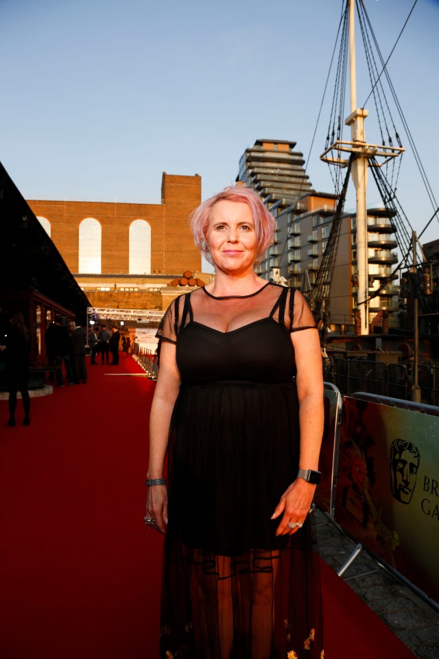 a woman in a black dress stands on a red carpet