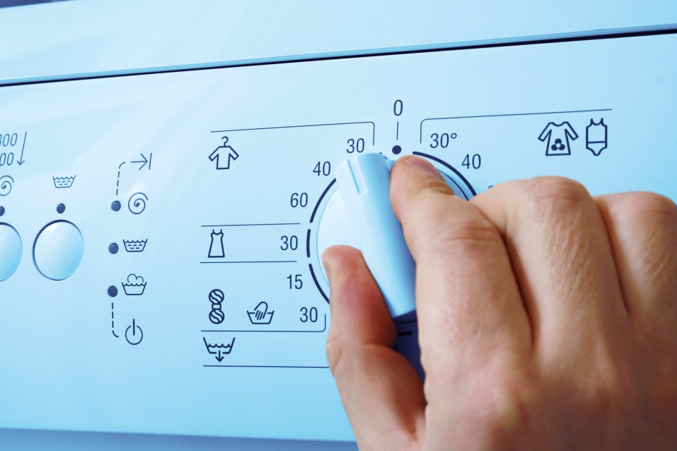 a person is adjusting the temperature of a washing machine