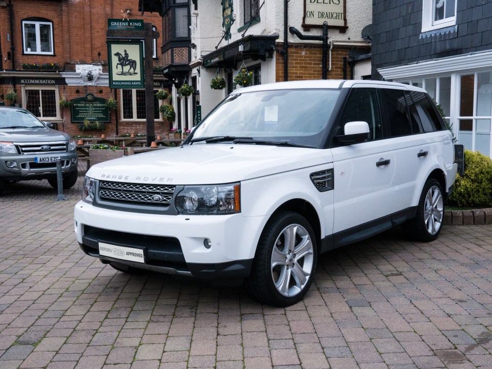 a white range rover is parked in front of the green king