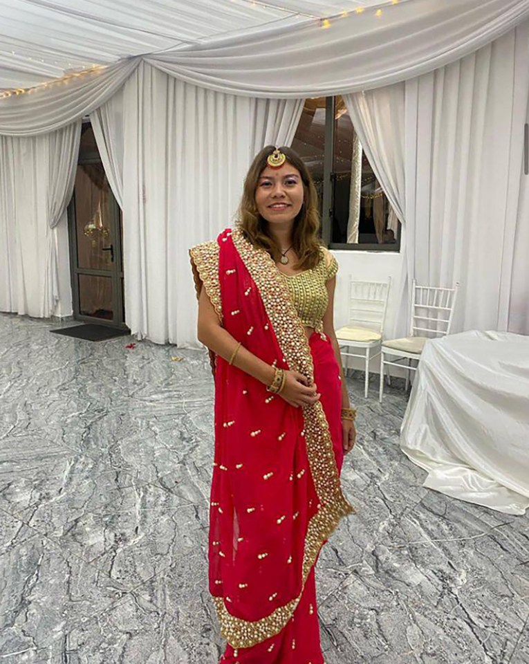 a woman in a red and gold dress stands in a room
