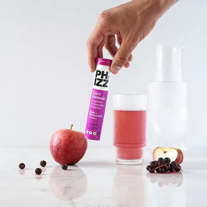 a hand is holding a tube of phizz effervescent tablets