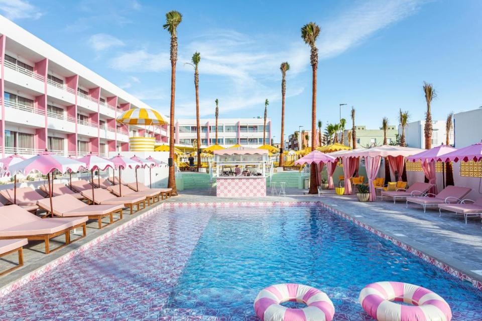 a large swimming pool surrounded by pink chairs and umbrellas
