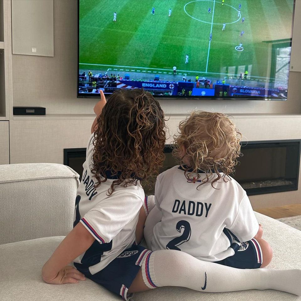 two children wearing daddy jerseys watch a soccer game