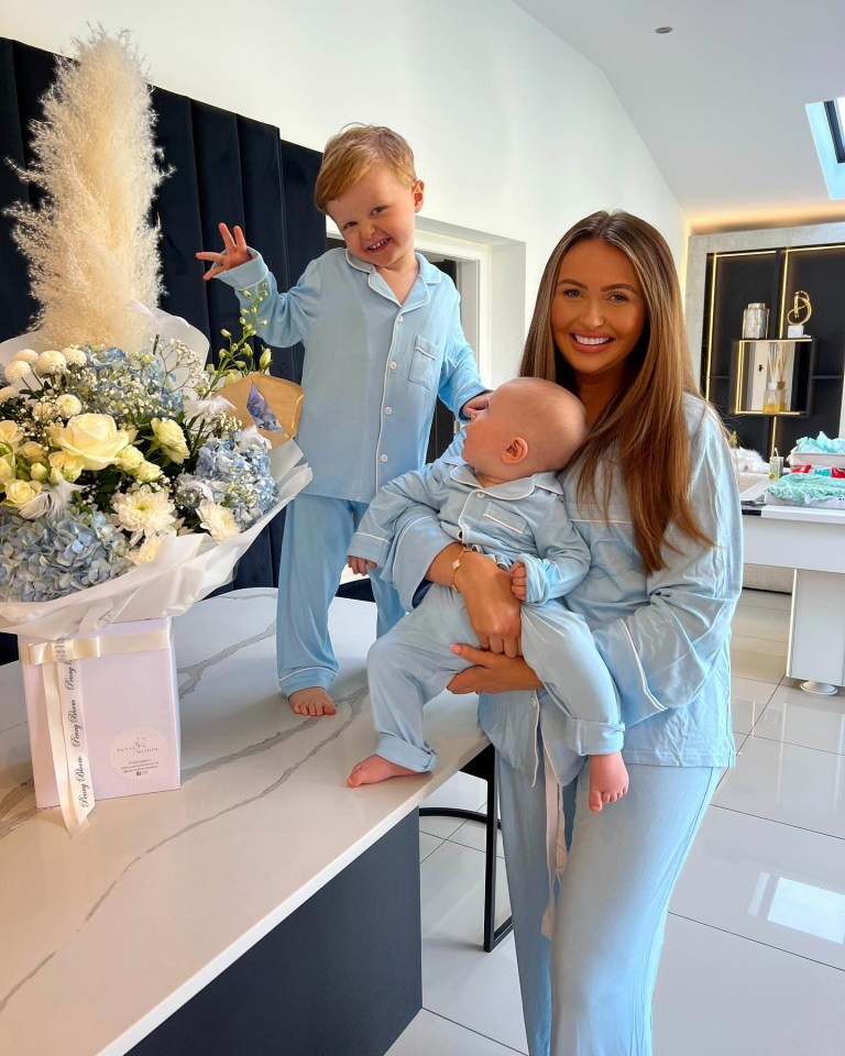 a woman holding a baby next to a bouquet of flowers