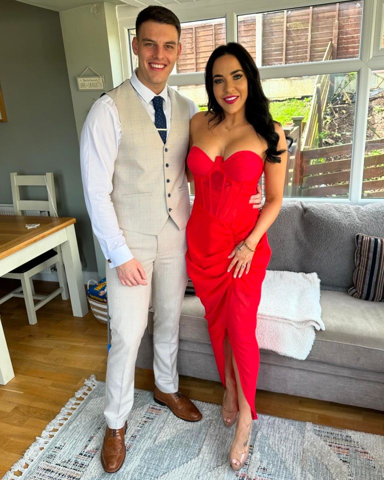 a man in a suit and tie stands next to a woman in a red dress