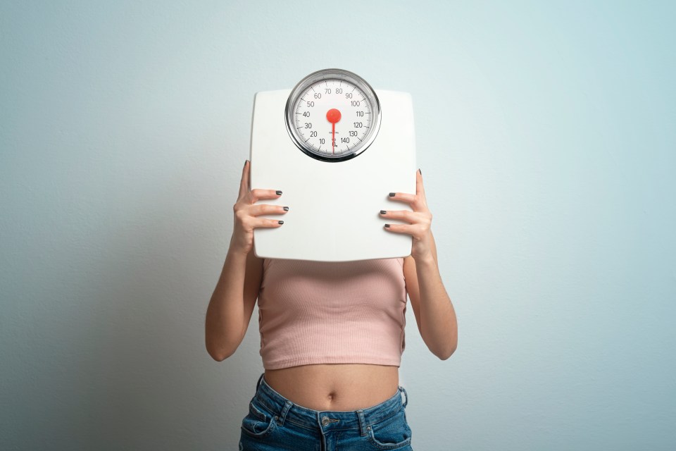 a woman is holding a scale in front of her face which shows a weight of 130 pounds