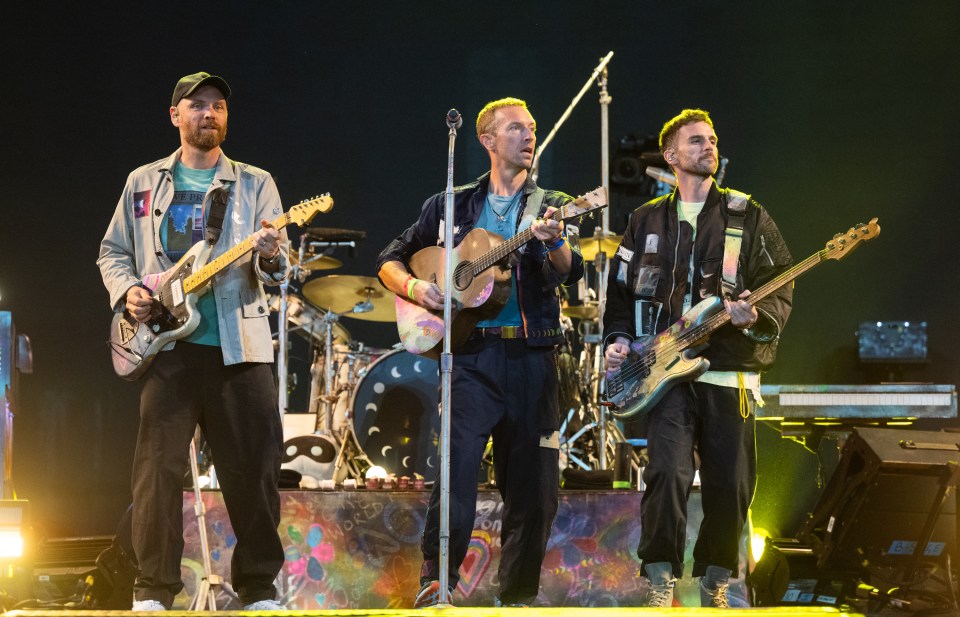 three men are on stage playing guitars and singing into microphones