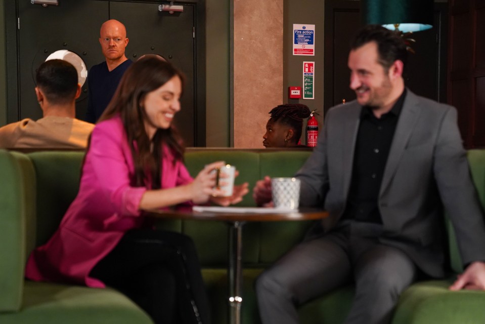a man in a suit sits next to a woman in a pink jacket