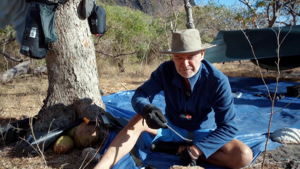 a man in a hat is sitting on a blue tarp with a bag that has the number 5 on it