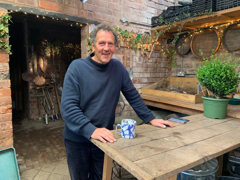 a man standing next to a wooden table with a blue and white mug on it