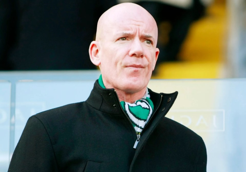 a bald man wearing a black jacket and a green scarf