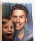 a man and a boy are posing for a picture and the boy is sticking his tongue out .