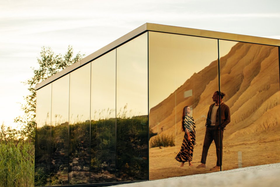 a man and a woman are standing in front of a mirrored building