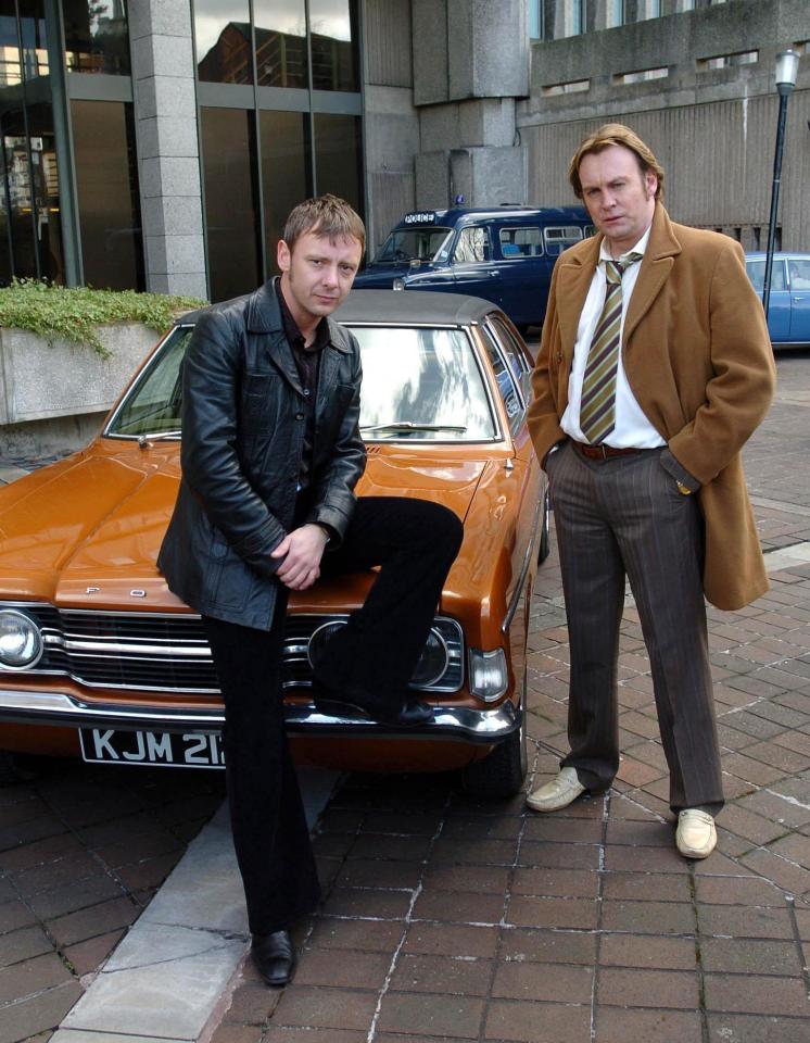 two men standing next to a car with license plate kjm 21