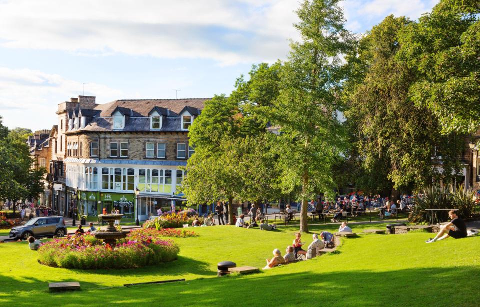 a group of people sit in a park in front of a building that says ' a & a ' on it