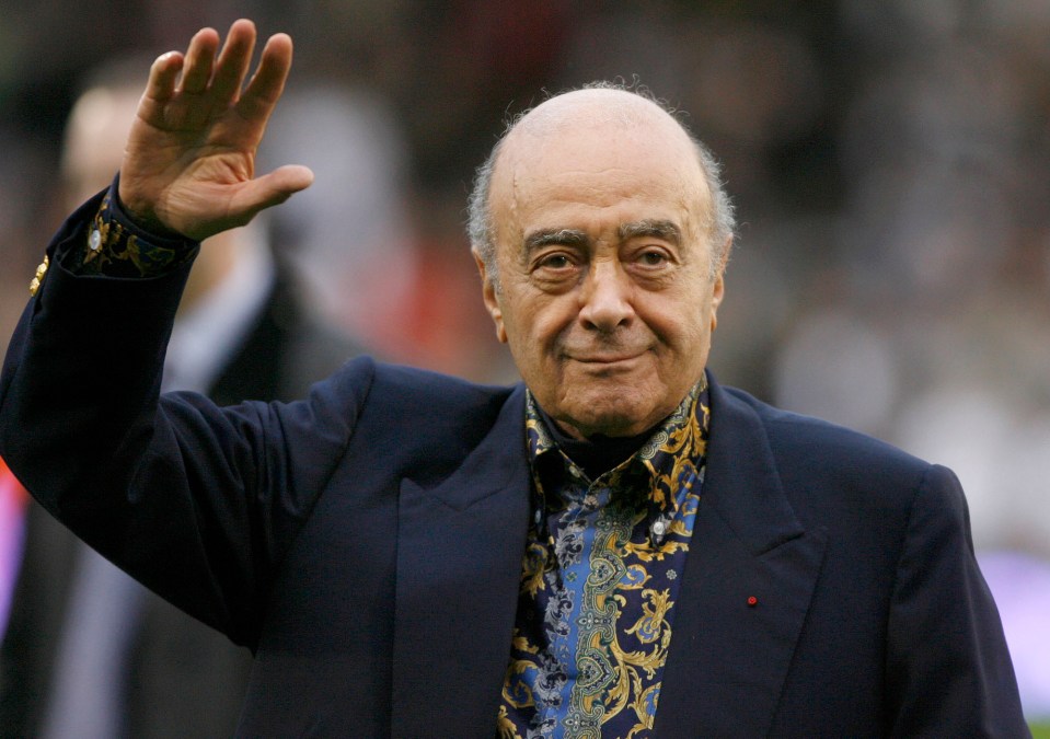 a man in a suit and paisley shirt waves his hand