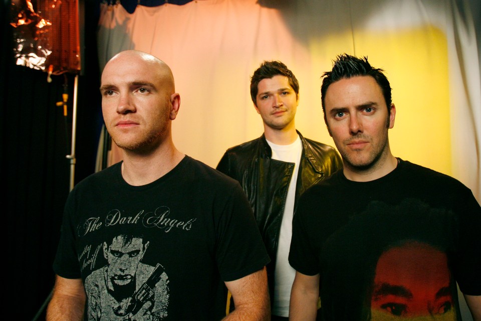 three men are posing for a picture and one of them is wearing a shirt that says the dark angels