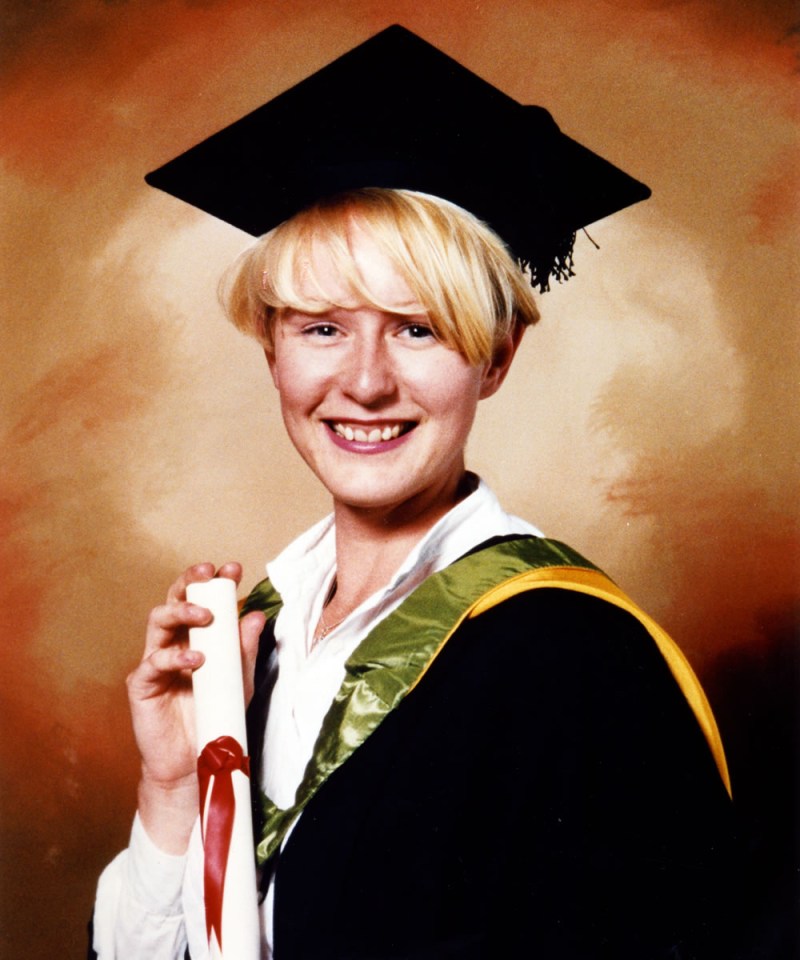 a woman in a graduation cap and gown holds a diploma