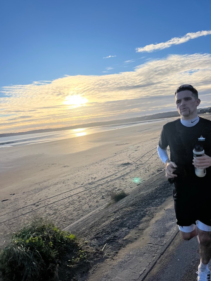 a man in a black nike shirt is running on the beach