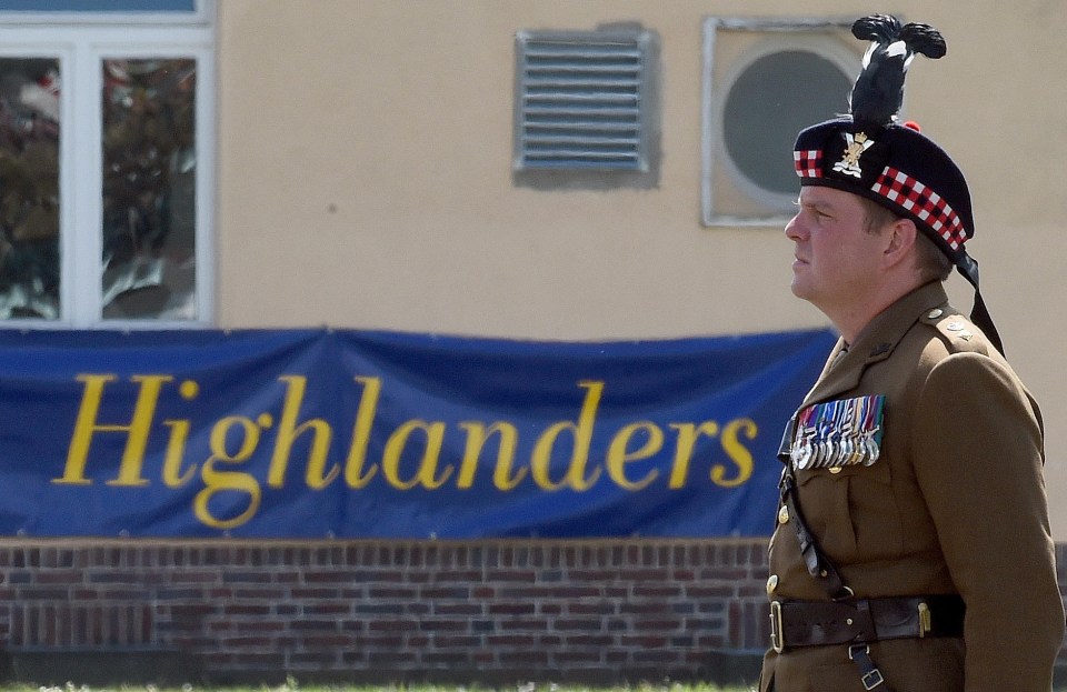 a man in a kilt stands in front of a banner that says highlanders