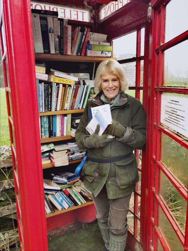 a woman standing in a red phone booth holding a book