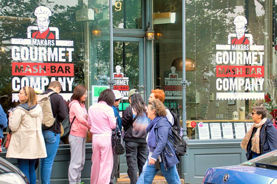 a group of people standing outside a maker 's gourmet mash bar company