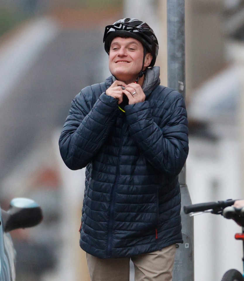a man wearing a helmet adjusts his jacket