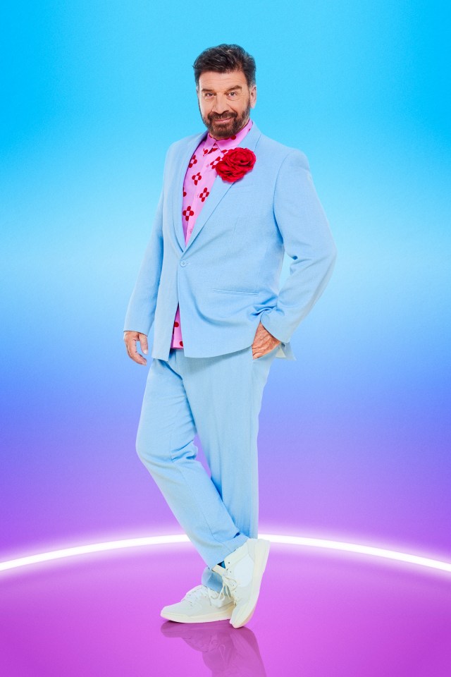 a man in a light blue suit with a red flower on his shirt