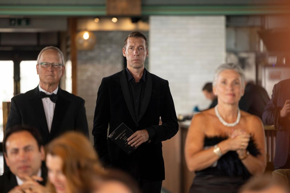 a man in a tuxedo is holding a book that says ' the bible ' on it