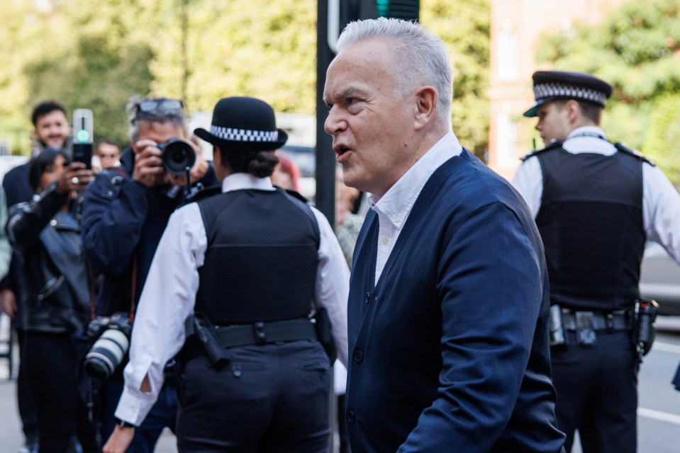 a man in a suit stands in front of two police officers