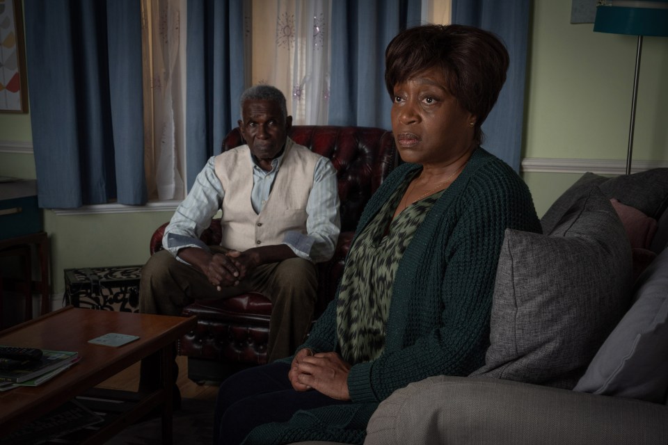 a man and a woman sit on a couch in a living room