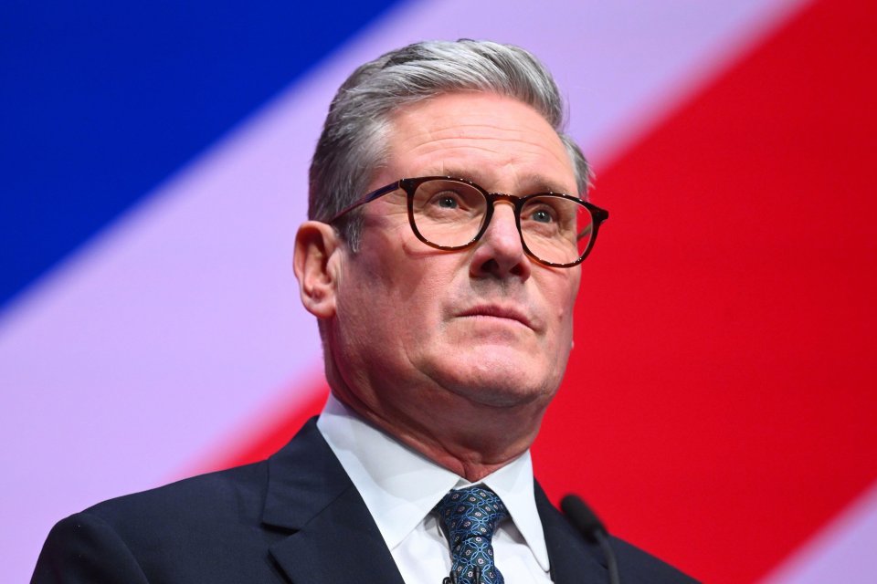 a man wearing glasses and a suit stands in front of a microphone
