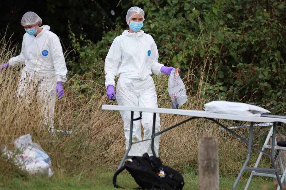 a woman in a hazmat suit holds a plastic bag