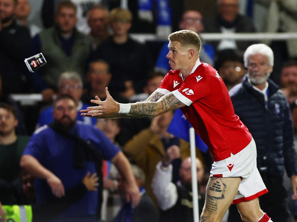 a soccer player with a tattoo on his leg throws a can of beer