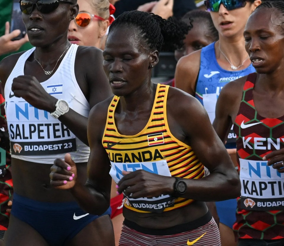 a group of runners with one wearing a yellow top that says ' uganda ' on it
