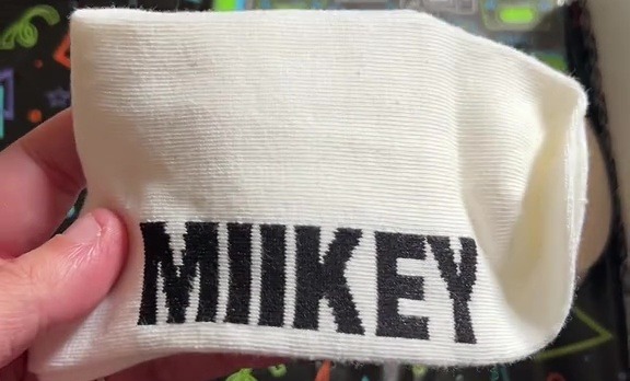 a person is holding a sock with the name miikey on it