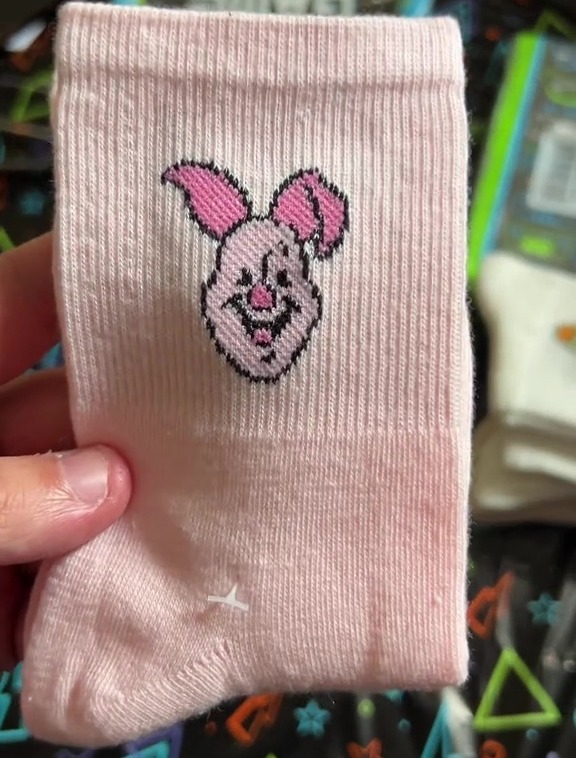 a person is holding a pair of pink socks with a pig on it