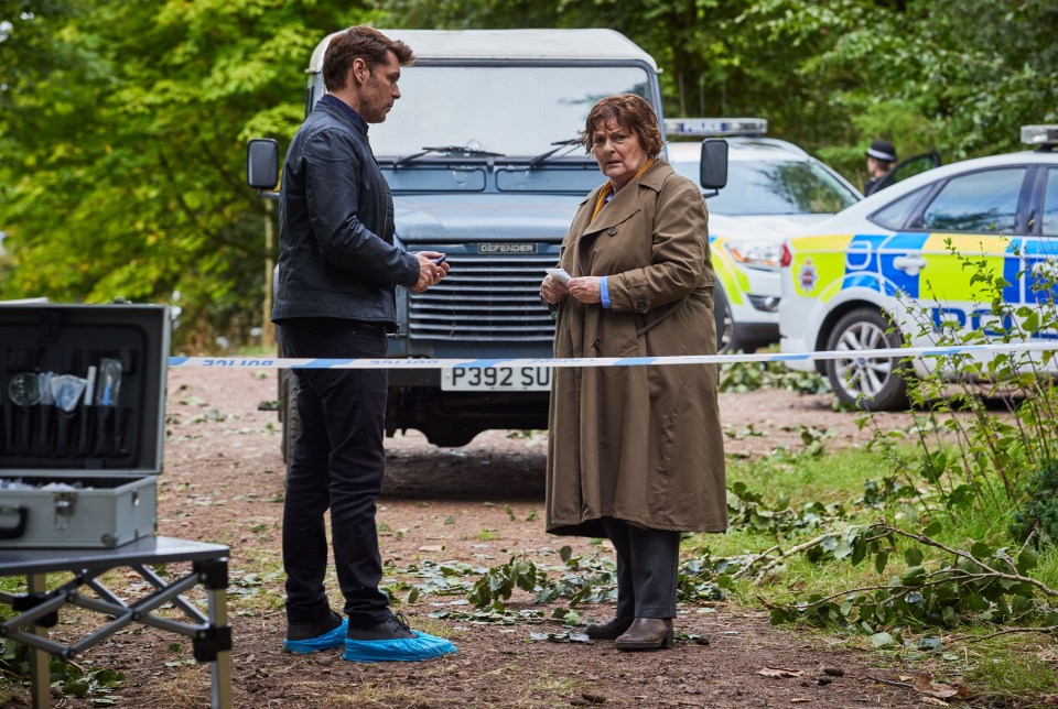 a man and a woman standing in front of a land rover