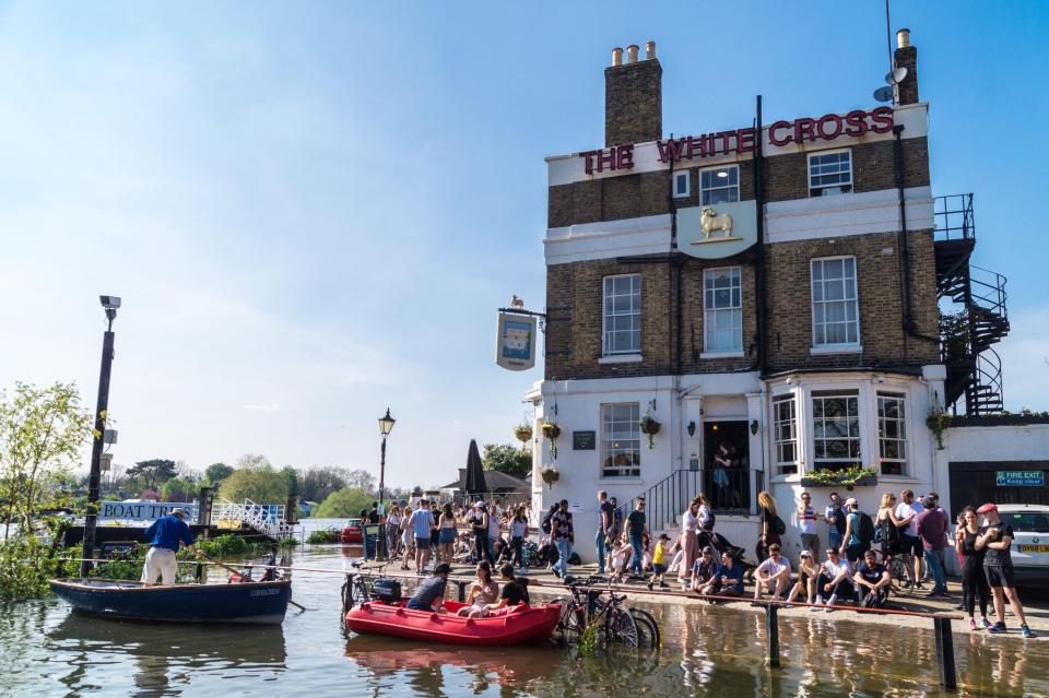 a group of people are gathered outside the white cross pub