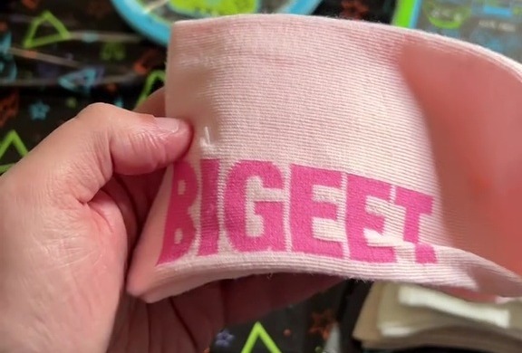 a person is holding a pink headband that says bigeet