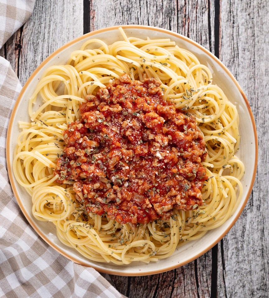 a plate of spaghetti with meat sauce on a wooden table