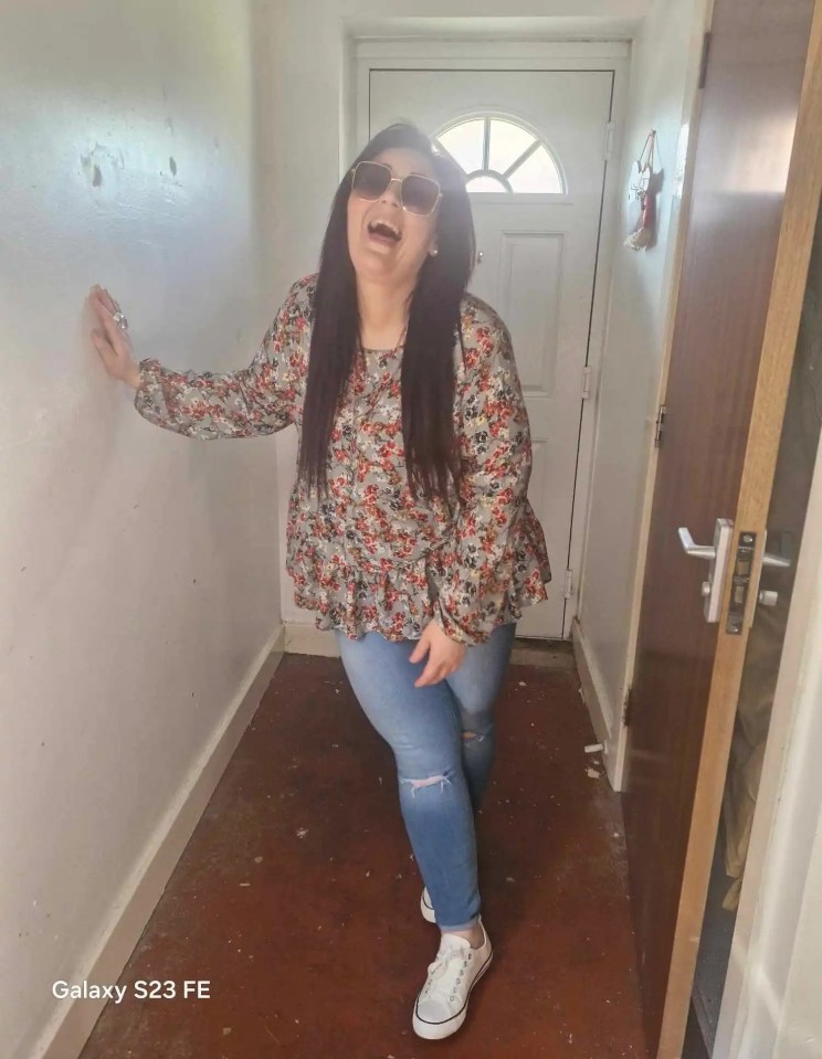 a woman wearing sunglasses is standing in a hallway with a galaxy s23 fe in the corner