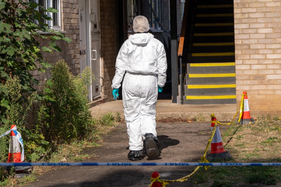a person in a white suit walks past a police tape