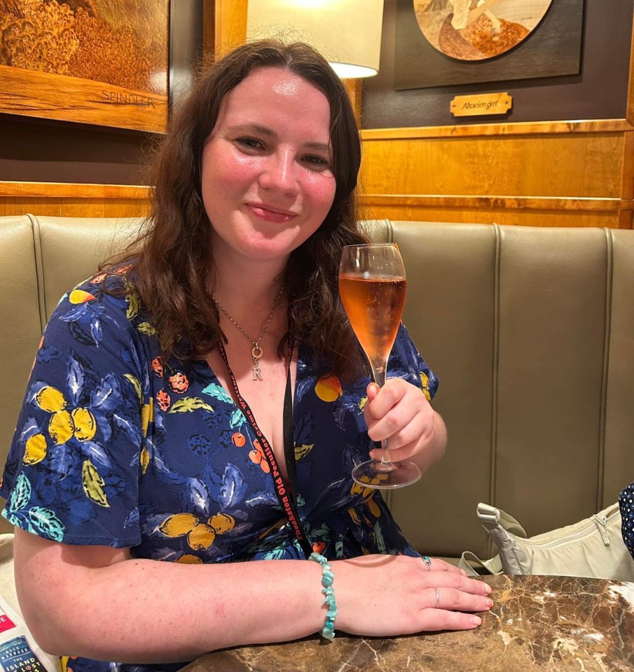 a woman sitting at a table holding a glass of wine