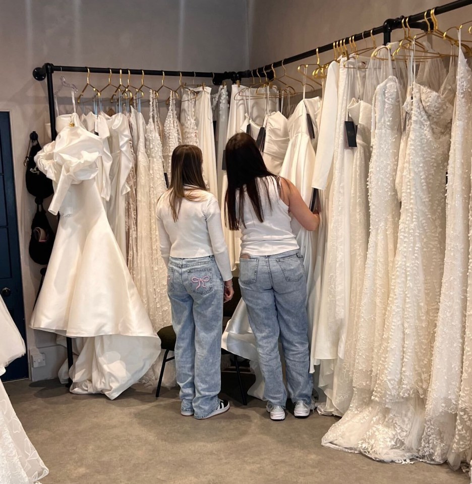 two women are looking at wedding dresses in a bridal shop