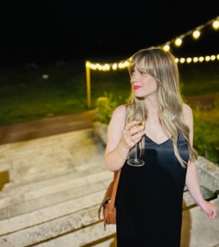 a woman in a black dress is holding a glass of champagne .