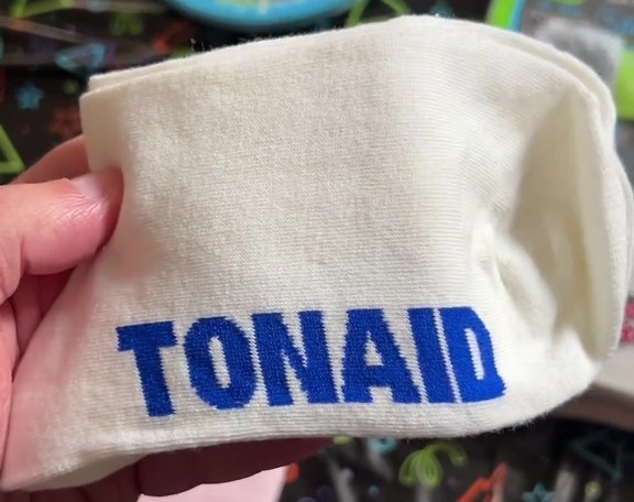 a person is holding a white towel with the name tonaid on it