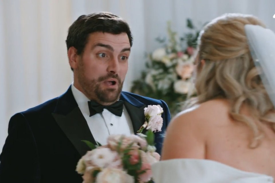 a man in a tuxedo stands next to a woman in a wedding dress