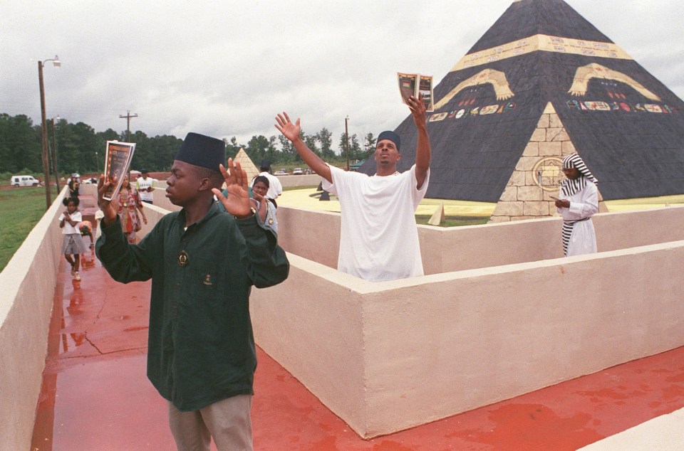 a group of people praying in front of a pyramid in eatonton georgia