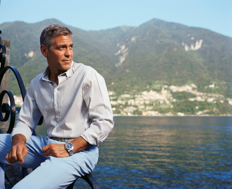a man in a striped shirt sits in front of a body of water